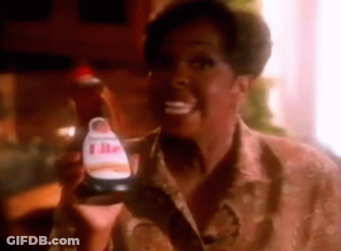 A Woman Is Smiling While Holding A Bottle Of Ketchup . GIF
