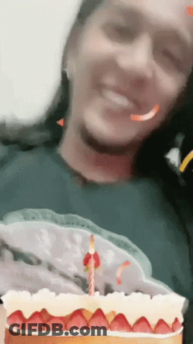 A Woman Is Smiling While Holding A Cake With Strawberries On It GIF
