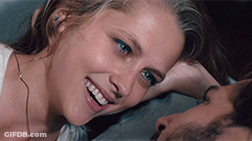 A Woman Is Smiling While Laying On A Man 'S Chest GIF