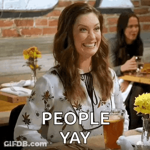 A Woman Is Smiling While Sitting At A Table With A Glass Of Beer And The Words `` People Yay '' . GIF