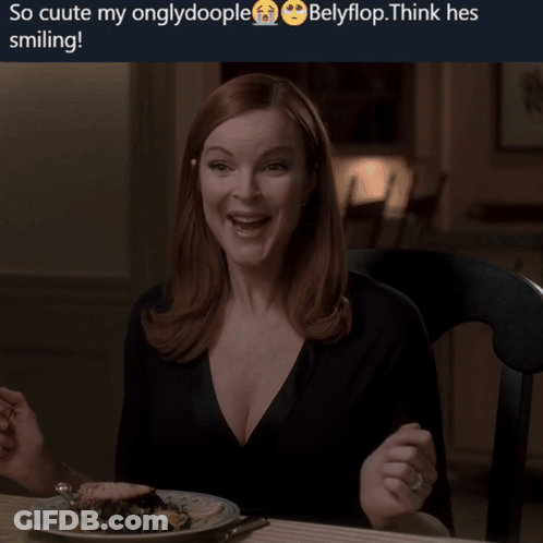 A Woman Is Smiling While Sitting At A Table With A Plate Of Food Behind Her GIF