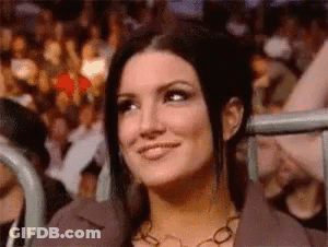 A Woman Is Smiling While Sitting In Front Of A Crowd Of People . GIF