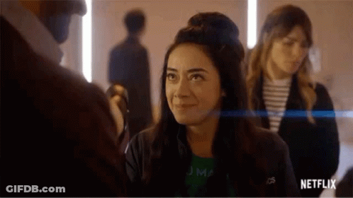 A Woman Is Smiling While Standing Next To A Man In A Room With Other People . GIF