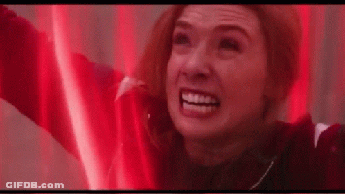 A Woman Is Smiling With Her Arms In The Air In A Red Light . GIF