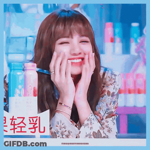 A Woman Is Smiling With Her Hands On Her Face In Front Of A Sign With Chinese Characters GIF