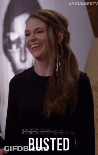 A Woman Is Smiling With The Word Busted Written On Her Chest GIF