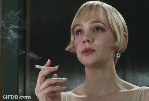 A Woman Is Smoking A Cigarette In Front Of A Window GIF