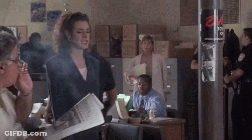 A Woman Is Smoking A Cigarette While Holding A Newspaper In Front Of A Group Of People . GIF