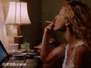 A Woman Is Smoking A Cigarette While Looking At A Laptop GIF