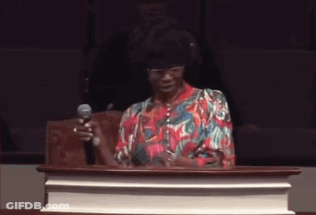 A Woman Is Standing At A Podium Holding A Microphone . GIF