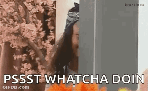 A Woman Is Standing Behind A Wall With Flowers In The Background And Says `` Pssst Whatcha Doin '' . GIF