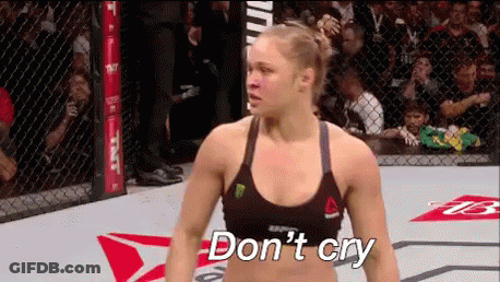 A Woman Is Standing In A Boxing Ring With The Words `` Don 'T Cry '' Written On The Floor . GIF