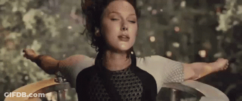 A Woman Is Standing In A Circle With Her Arms Outstretched And Her Eyes Closed . GIF