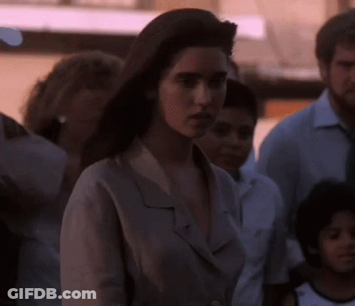 A Woman Is Standing In A Crowd Of People And Looking At The Camera GIF