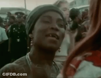 A Woman Is Standing In A Crowd Of People And Smiling . GIF