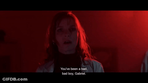 A Woman Is Standing In A Dark Room And Talking To A Boy . GIF