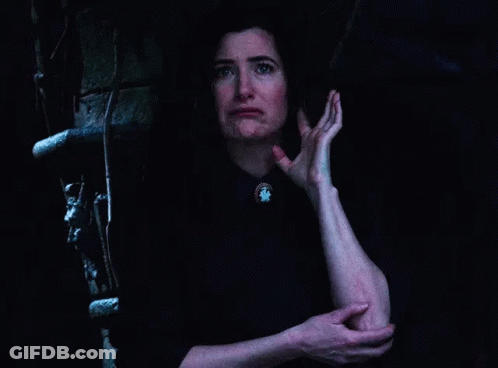 A Woman Is Standing In A Dark Room Holding Her Elbow . GIF