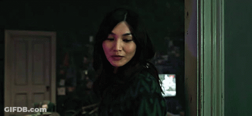 A Woman Is Standing In A Dark Room In Front Of A Door . GIF