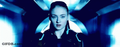 A Woman Is Standing In A Dark Room With A Blue Light Behind Her And Looking At The Camera . GIF