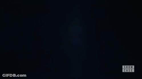 A Woman Is Standing In A Dark Room With Her Eyes Closed And A Show Case Logo In The Corner . GIF