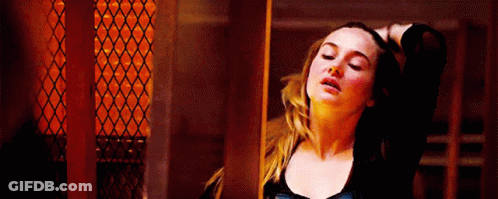 A Woman Is Standing In A Dark Room With Her Hand On Her Head . GIF