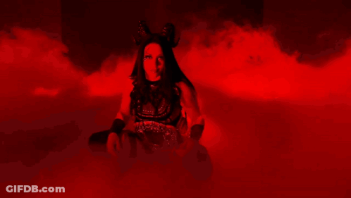 A Woman Is Standing In A Dark Room With Red Smoke Coming Out Of It GIF