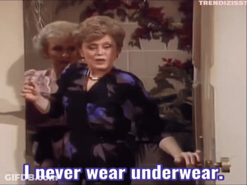 A Woman Is Standing In A Doorway Holding A Glass And Saying " I Never Wear Underwear " GIF