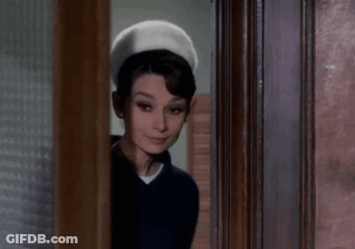 Woman Standing In Doorway Wearing Hat And Blue Shirt GIF