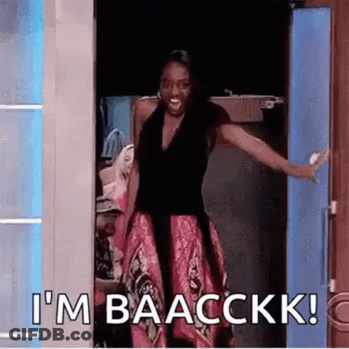 A Woman Is Standing In A Doorway With Her Arms Outstretched And Says `` I 'M Baacckkk '' . GIF