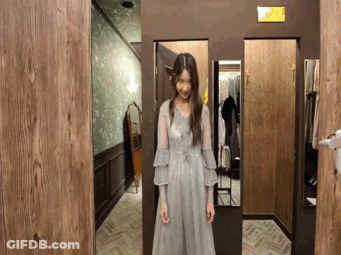 A Woman Is Standing In A Dressing Room With A Sign That Says Exit GIF