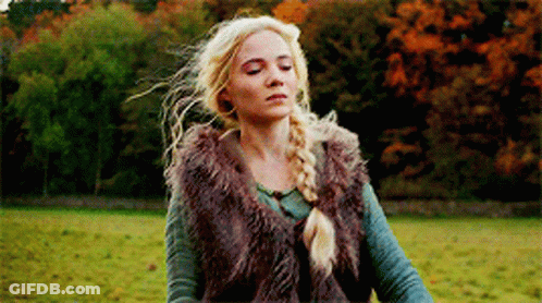 A Woman Is Standing In A Field Wearing A Fur Vest . GIF