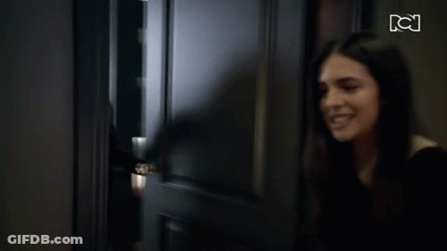A Woman Is Standing In A Hallway With A Tv Screen Behind Her That Says Tci GIF