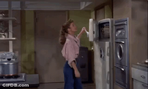 A Woman Is Standing In A Kitchen With Her Back To The Camera . GIF