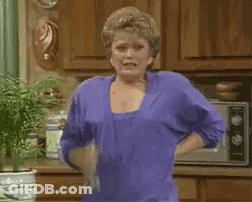 A Woman Is Standing In A Kitchen With Her Hands On Her Hips . GIF