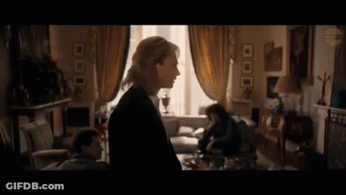 A Woman Is Standing In A Living Room Next To A Man And A Woman . GIF