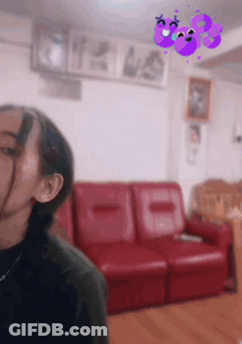 A Woman Is Standing In A Living Room With A Red Couch And A Purple Butterfly On The Wall . GIF