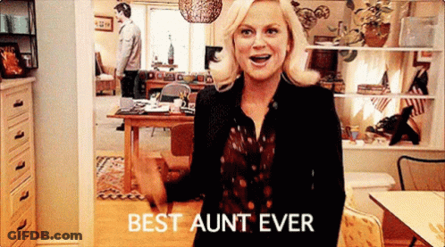 A Woman Is Standing In A Living Room With The Words `` Best Aunt Ever '' On Her Shirt . GIF