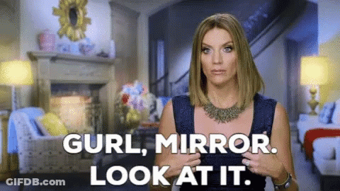 A Woman Is Standing In A Living Room With The Words " Curl Mirror Look At It " GIF