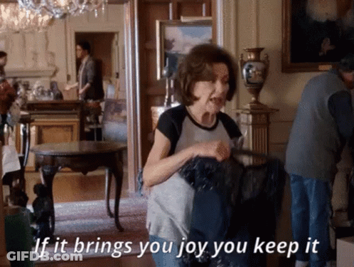 A Woman Is Standing In A Room Holding A Black Bag And Says If It Brings You Joy You Keep It . GIF