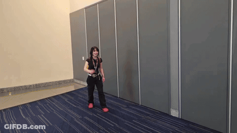 A Woman Is Standing In A Room With A Blue Carpet And A Gray Wall GIF