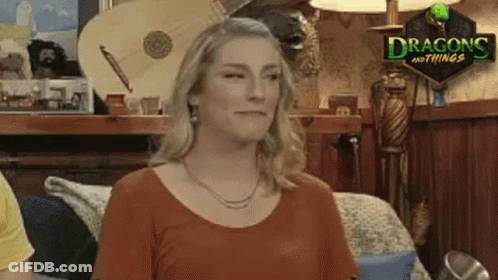 A Woman Is Standing In A Room With A Sign That Says Dragons And Things On It . GIF