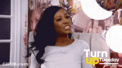 A Woman Is Standing In A Room With Balloons And A Sign That Says Turn Up Tuesday GIF