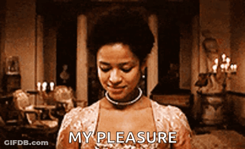 A Woman Is Standing In A Room With The Words My Pleasure Written On Her Chest GIF