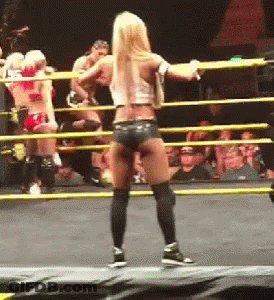 A Woman Is Standing In A Wrestling Ring With A Crowd In The Background GIF