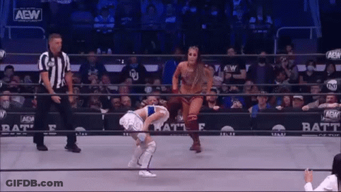 A Woman Is Standing In A Wrestling Ring With A Referee . GIF