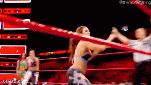 A Woman Is Standing In A Wrestling Ring With A Referee . GIF