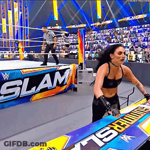 A Woman Is Standing In A Wrestling Ring With A Sign That Says Slam . GIF