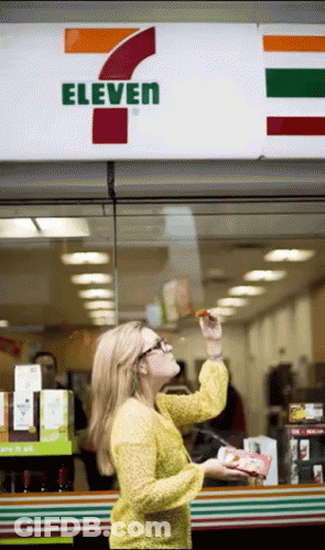 A Woman Is Standing In Front Of A 7 Eleven GIF