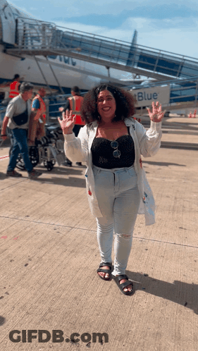 A Woman Is Standing In Front Of A Blue Airplane GIF