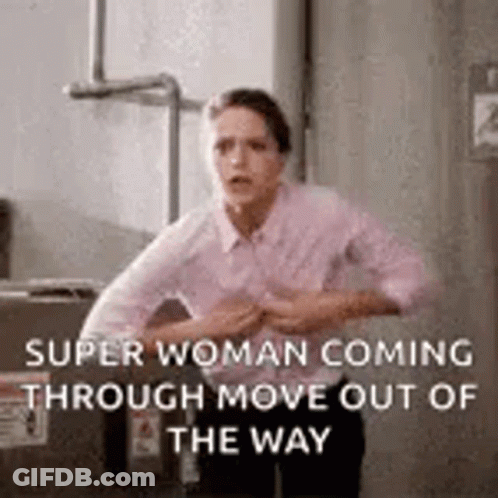 A Woman Is Standing In Front Of A Box And Holding Her Chest . GIF